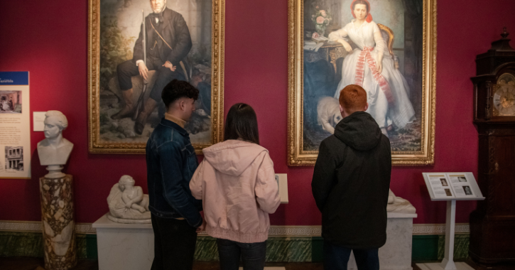 Group of teenages stood admiring the portrait portraits of The Bowes Museum founders John and Josephine Bowes.